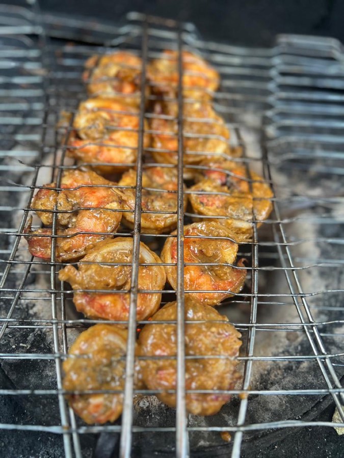Marinated prawns grilling over open flame